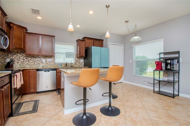 kitchen with plenty of natural light, stainless steel appliances, light stone countertops, and a kitchen island