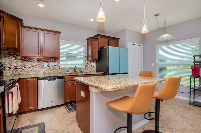 kitchen featuring decorative light fixtures, stainless steel appliances, a center island, decorative backsplash, and a breakfast bar