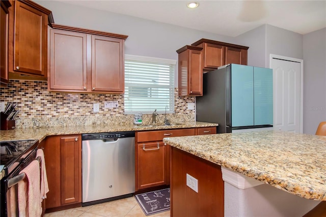 kitchen with light tile patterned floors, stainless steel appliances, light stone counters, sink, and decorative backsplash