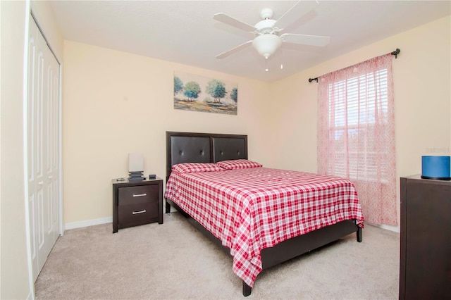 bedroom with light colored carpet, ceiling fan, and a closet