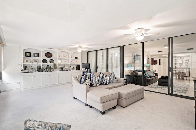 living room featuring light carpet, built in shelves, and ceiling fan