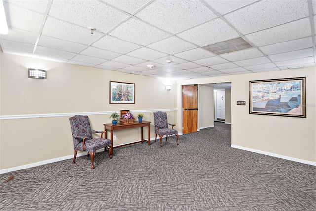 sitting room featuring a paneled ceiling and dark carpet