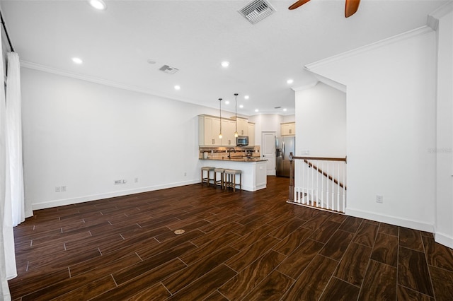 unfurnished living room featuring ceiling fan, sink, dark hardwood / wood-style floors, and crown molding