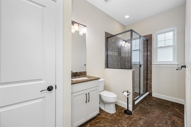 bathroom with toilet, vanity, and a shower with door