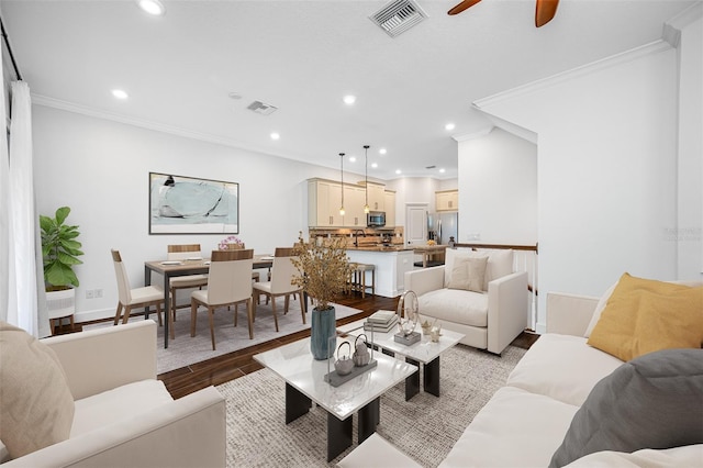 living room featuring ornamental molding, ceiling fan, and light hardwood / wood-style flooring