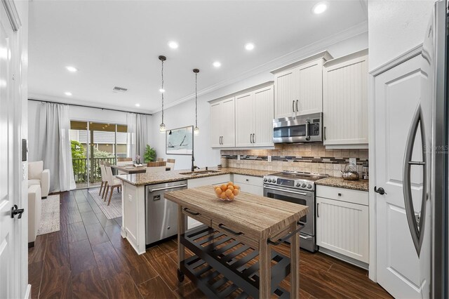 kitchen featuring appliances with stainless steel finishes, ornamental molding, light stone countertops, decorative light fixtures, and dark wood-type flooring