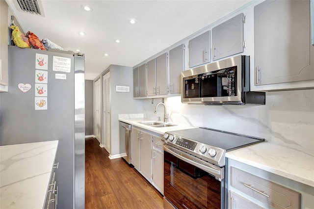 kitchen featuring light stone counters, gray cabinets, stainless steel appliances, hardwood / wood-style floors, and sink