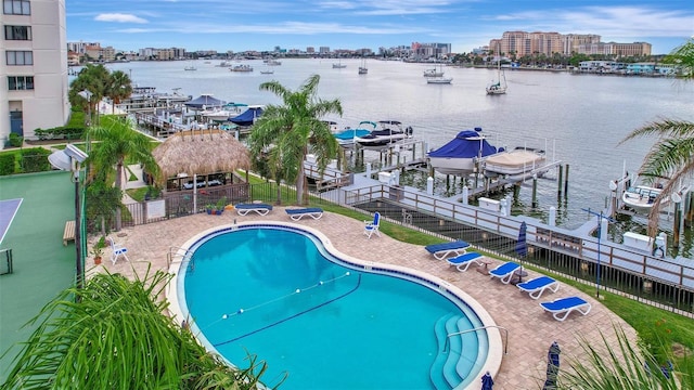 view of swimming pool with a dock, a patio, and a water view