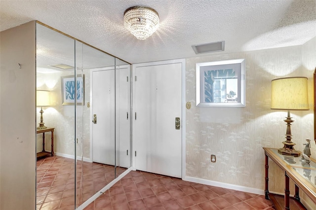 entryway featuring an inviting chandelier and a textured ceiling