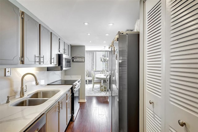 kitchen with light stone countertops, gray cabinets, stainless steel appliances, dark hardwood / wood-style floors, and sink