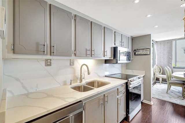 kitchen featuring dark hardwood / wood-style floors, tasteful backsplash, sink, gray cabinetry, and stainless steel appliances