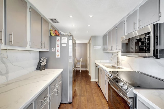 kitchen with gray cabinets, stainless steel appliances, sink, and hardwood / wood-style flooring