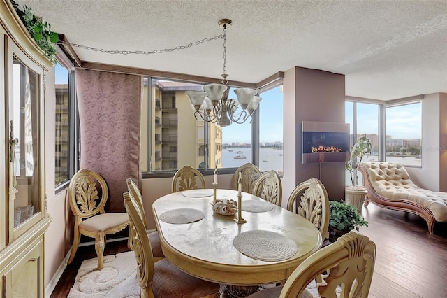 dining room with a notable chandelier, a textured ceiling, a water view, and hardwood / wood-style flooring