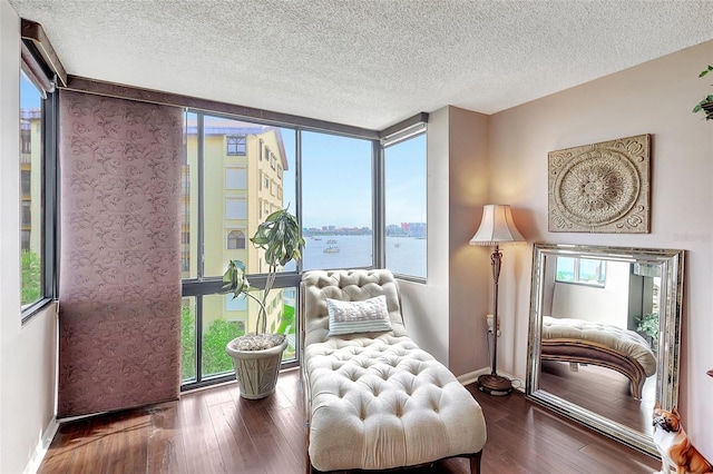 sitting room with a wall of windows, a water view, dark wood-type flooring, and a wealth of natural light