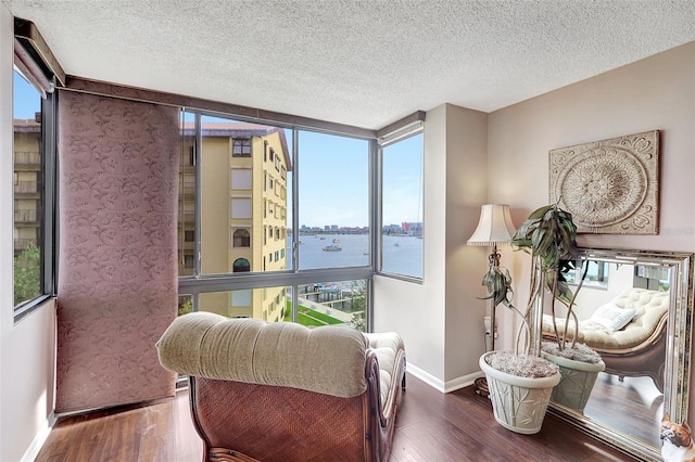 sitting room with dark hardwood / wood-style flooring, a water view, and a healthy amount of sunlight