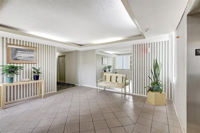 interior space featuring a textured ceiling, light tile patterned flooring, and a tray ceiling