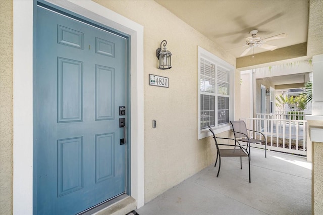 view of exterior entry with a porch and ceiling fan