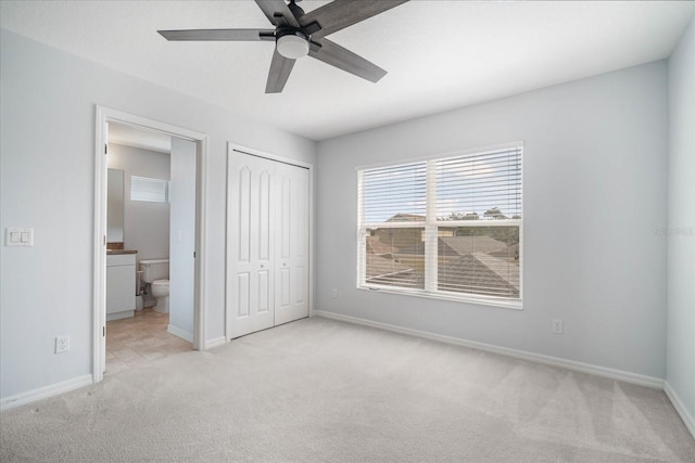 unfurnished bedroom with light carpet, ensuite bathroom, ceiling fan, and a closet