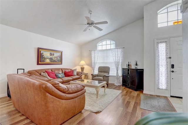 living room featuring a textured ceiling, ceiling fan, high vaulted ceiling, and light hardwood / wood-style floors