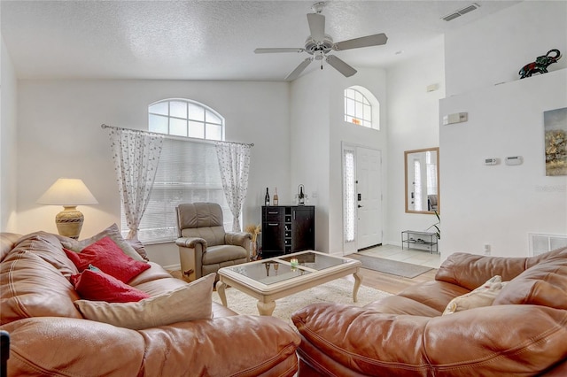 tiled living room with a textured ceiling, high vaulted ceiling, and ceiling fan