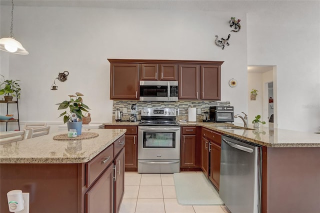 kitchen with backsplash, hanging light fixtures, appliances with stainless steel finishes, sink, and light tile patterned flooring