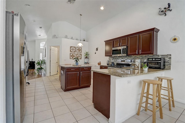 kitchen featuring light stone countertops, pendant lighting, light hardwood / wood-style floors, stainless steel appliances, and kitchen peninsula