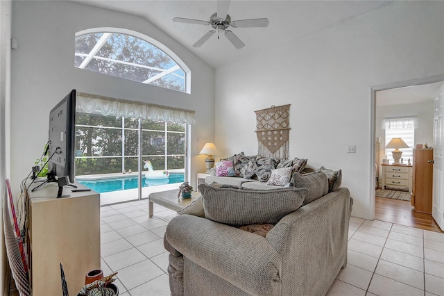 tiled living room featuring a wealth of natural light, ceiling fan, and high vaulted ceiling