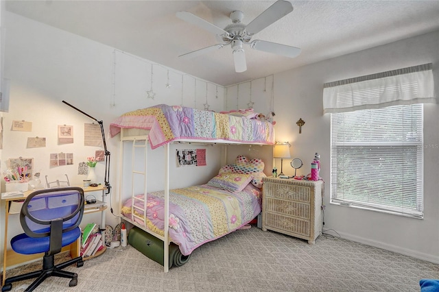 carpeted bedroom featuring ceiling fan and a textured ceiling