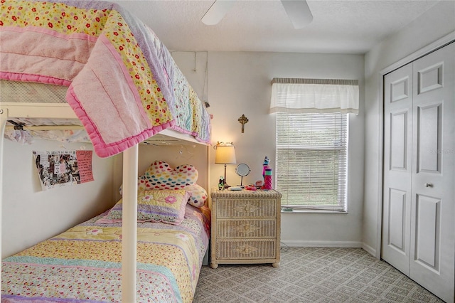 bedroom featuring light carpet, a textured ceiling, ceiling fan, and a closet