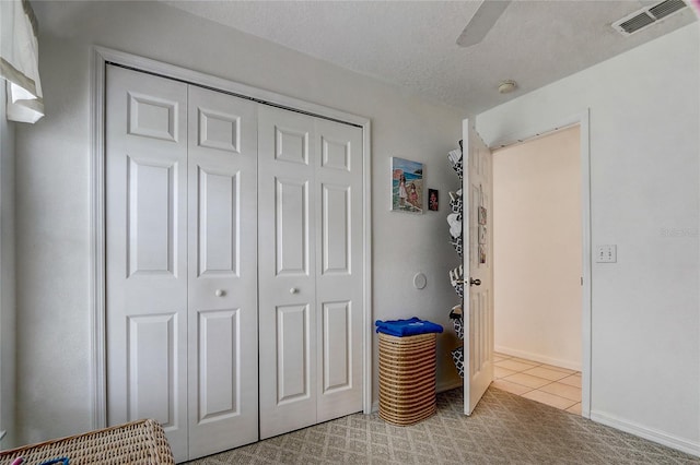 unfurnished bedroom with a textured ceiling, ceiling fan, a closet, and light carpet