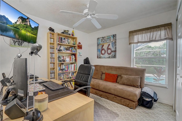 office space featuring a textured ceiling, ceiling fan, and light carpet