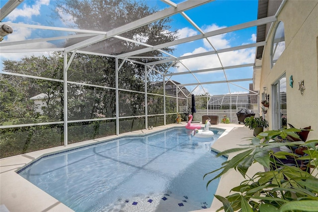 view of pool featuring glass enclosure, a patio area, and area for grilling