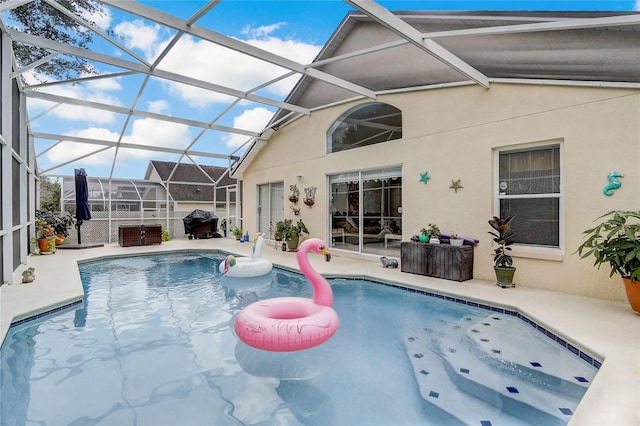 view of swimming pool featuring glass enclosure and a patio