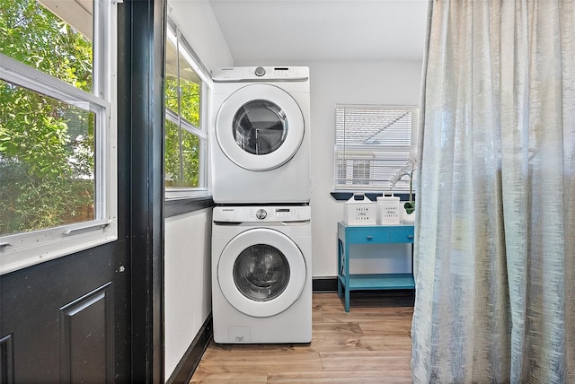 laundry area featuring stacked washing maching and dryer and light wood-type flooring