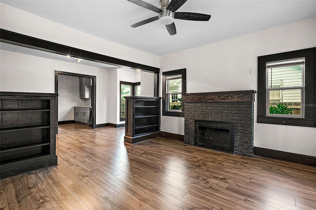 living room featuring hardwood / wood-style floors, ceiling fan, a fireplace, and a textured ceiling