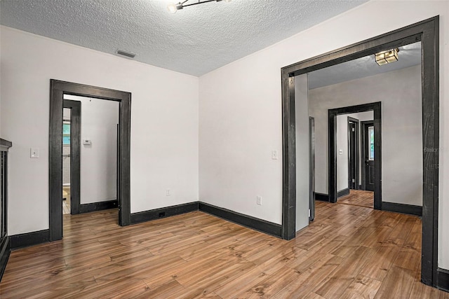 spare room featuring a textured ceiling and hardwood / wood-style flooring