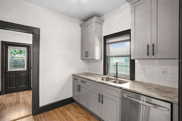 kitchen featuring gray cabinetry, dishwasher, sink, light hardwood / wood-style flooring, and backsplash