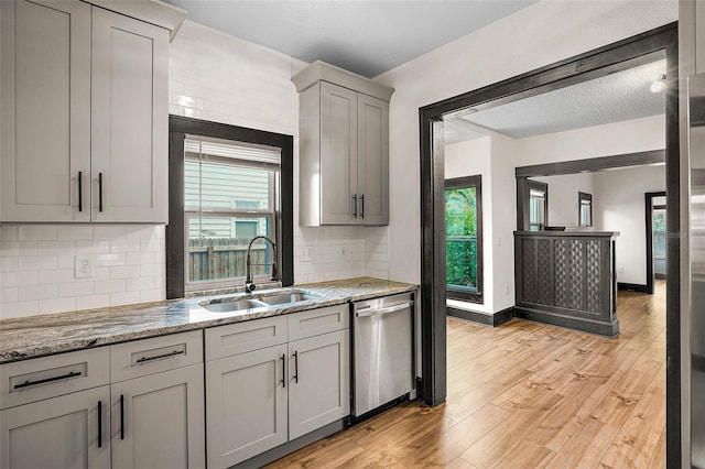 kitchen with backsplash, sink, light hardwood / wood-style flooring, dishwasher, and gray cabinets