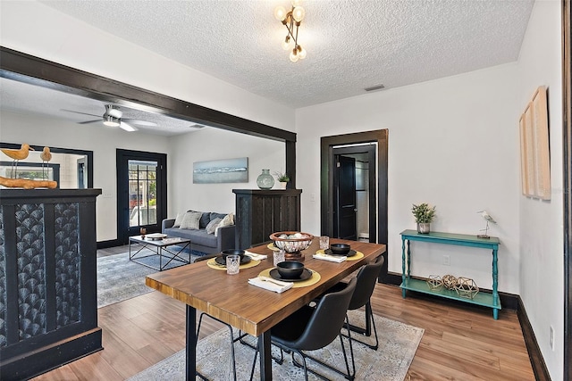 dining room featuring wood-type flooring, a textured ceiling, and ceiling fan