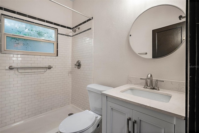 bathroom with toilet, vanity, and tiled shower