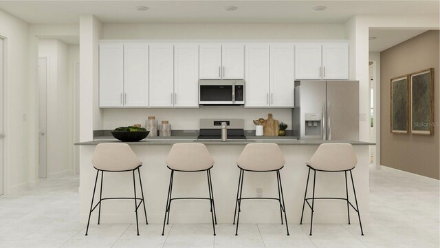 kitchen with white cabinets, appliances with stainless steel finishes, a center island with sink, and a breakfast bar