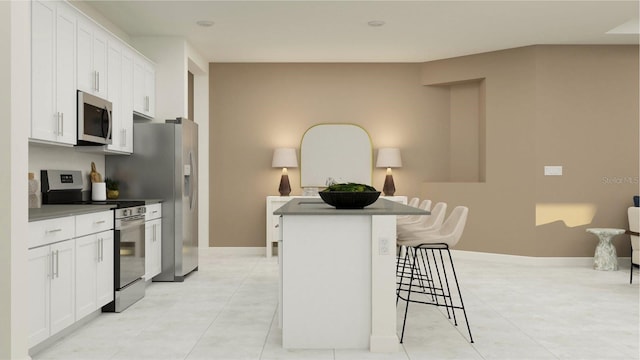 kitchen featuring a breakfast bar, white cabinetry, stainless steel appliances, light tile patterned floors, and baseboards