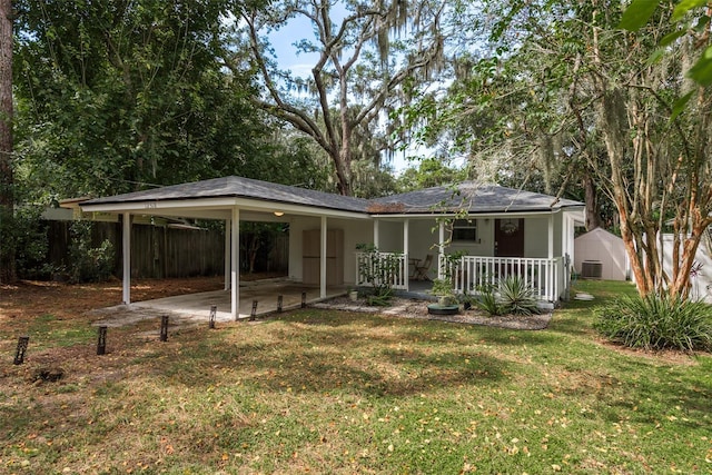 rear view of property featuring a carport, cooling unit, a yard, fence, and covered porch