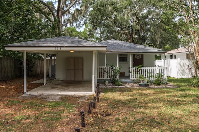 exterior space with a yard, a porch, fence, and an attached carport