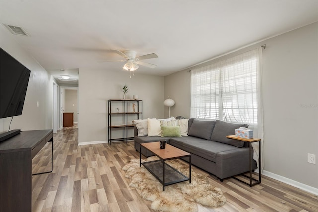 living room with visible vents, baseboards, light wood finished floors, and a ceiling fan