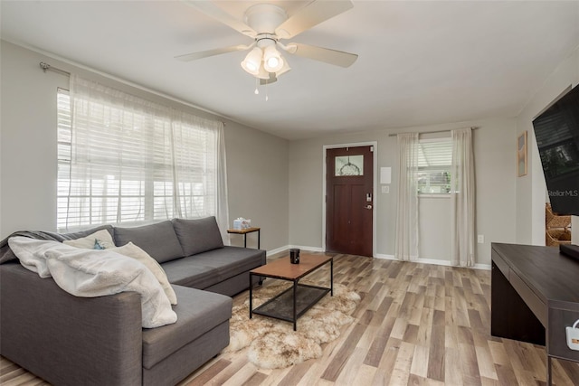 living room with light wood-style flooring, ceiling fan, and baseboards