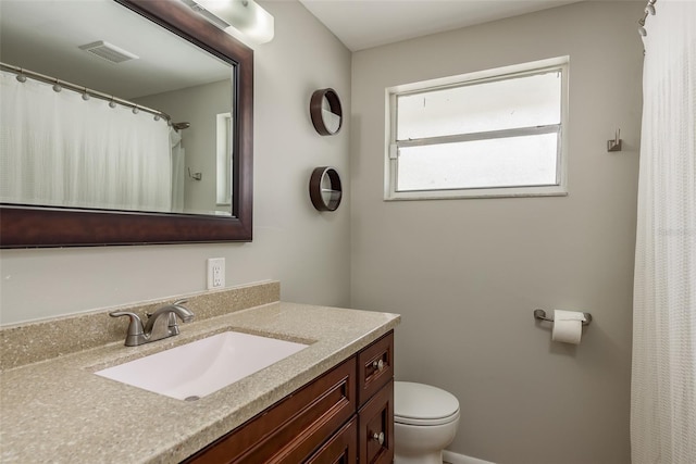 full bathroom featuring toilet, vanity, visible vents, and a shower with curtain
