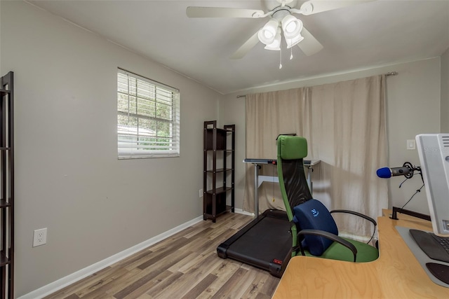 exercise area with baseboards, a ceiling fan, and wood finished floors