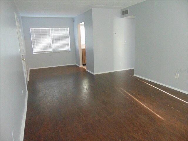 unfurnished room featuring visible vents, baseboards, and wood finished floors