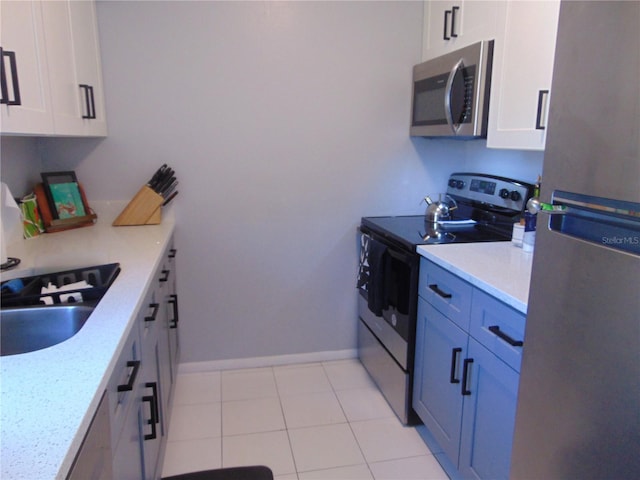 kitchen featuring a sink, appliances with stainless steel finishes, white cabinets, and light countertops